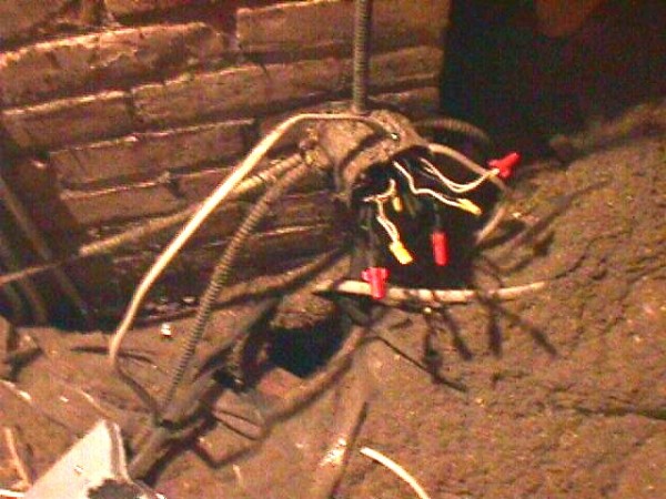 A spider is sitting on the ground with wires.